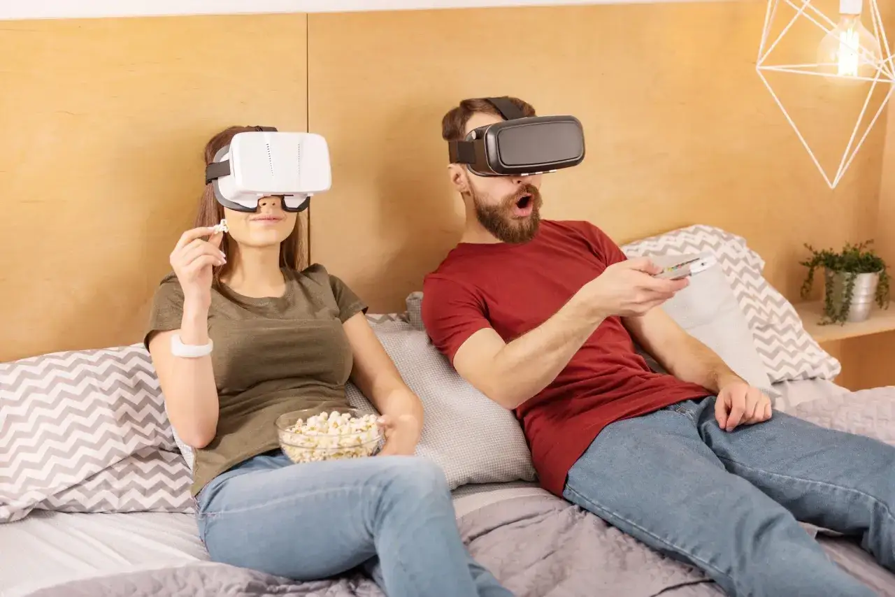 Para w goglach VR ogląda film, jedząc popcorn.